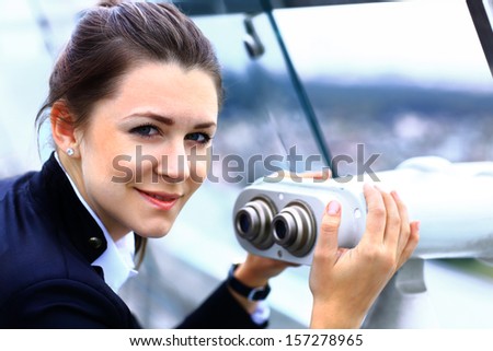 Businesswoman looks through telescope on the city building