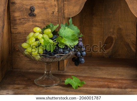 Grapes in glass vase on vintage wooden cupboard