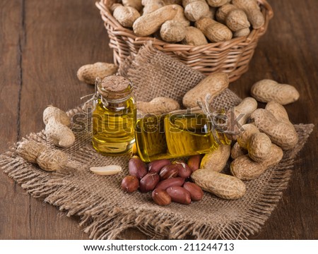 Peanut oil in a glass bottles with raw peanuts on wooden table