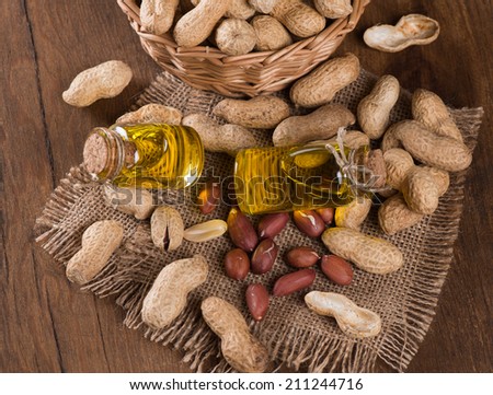 Top view of bottles of peanut oil with nuts on wooden table