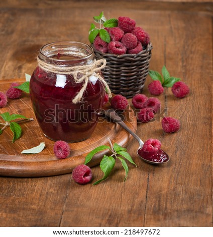 Raspberries, jam in glass jar on wooden table  with copy-space