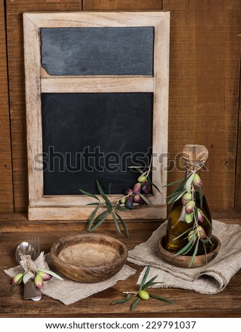 Olive table setting with wooden bowls, gray textile napkin and branch of olive on old wooden table