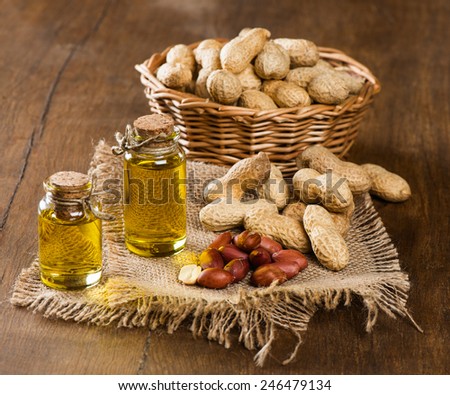 Peanut oil in bottles and nuts on a wooden background