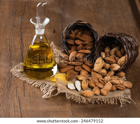 Almond kernels, whole and almond oil on rustic old wooden table