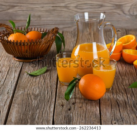 Fresh orange juice and fruits and green leaves on the wooden table, selective focus