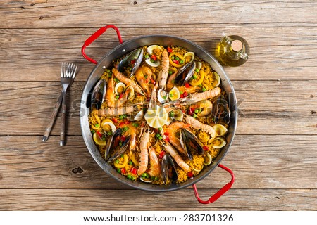 View from above of paella with seafood in a paellera on a wooden background with copy space