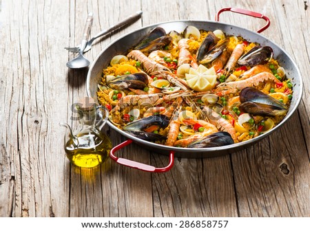 Spanish dish paella with seafood  in traditional pan on a rustic wooden table