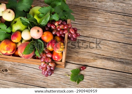 Top view of assortment of fruits in box on wooden table with space for text