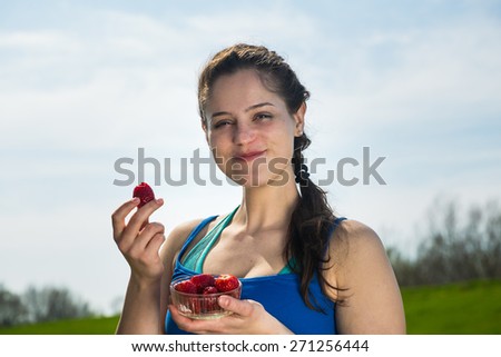 Smiling young woman eating fresh strawberries at the workout a healthy food for body .