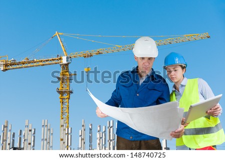 Foreman and engineer with blueprints at construction site