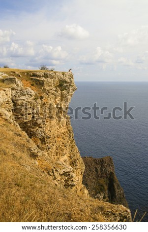 Lonely Man sitting on edge of the cliff in Fiolent cape, Crimea