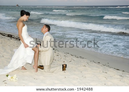 Groom removing the brides garter belt on the beach.