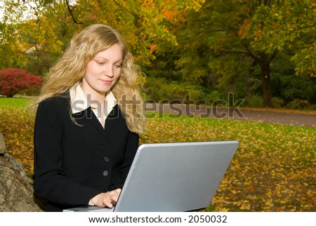 Women with laptop studying in the park in Autumn.