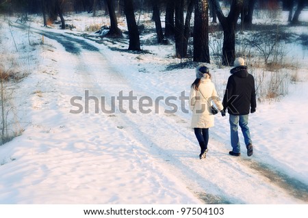 young beautiful couple having a walk in winter park