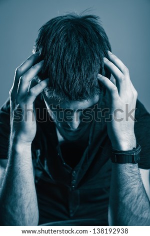 Sad man looking down with his hands on head