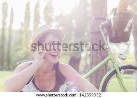 Beautiful young woman using mobile phone sitting next to her bike Beautiful young woman using mobile phone sitting next to her bike