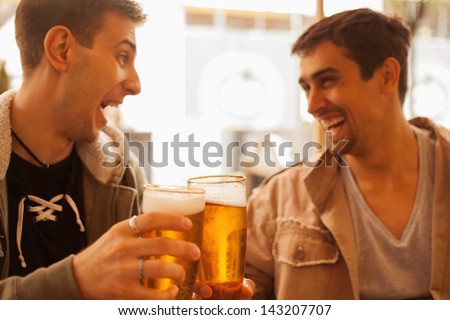Young cheerful men having fun drinking beer outdoors.