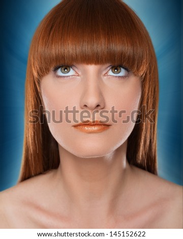 Beauty portrait of red haired gorgeous woman on blue background