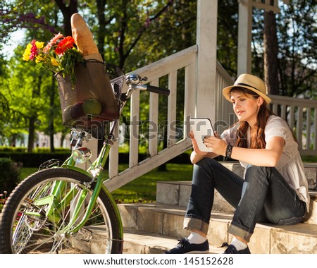 Young woman using digital tablet next to her bicycle.