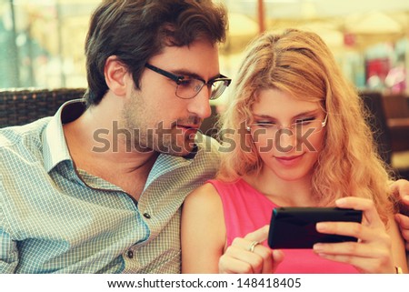 Close up of a young couple enjoying in cafe using smart phone.