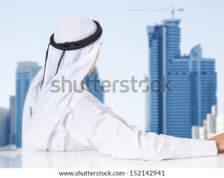 Successful Arab businessman looking out the window of his office.