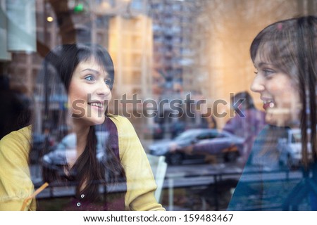 Two Young Girls Having Conversation In A Cafe. The Photo Was Taken Through The Window
