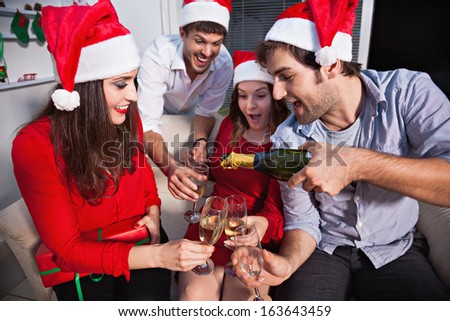 Young people wearing Santa's hats drinking champagne on new year's eve.
