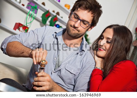 Young happy couple opening champagne on New Year\'s eve.