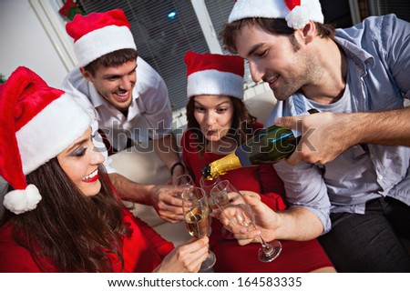 Young people wearing Santa\'s hats drinking champagne on new year\'s eve.