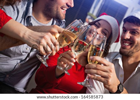 Young people wearing Santa\'s hats having a toast with champagne on new year\'s eve.