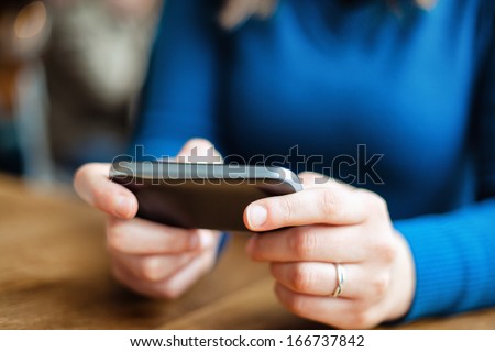 Close up of a young woman typing text message on her smartphone. Focus is on the phone.