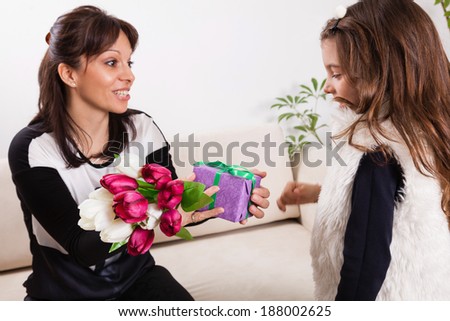 Cute little girl giving her mother flowers for Mother\'s day.