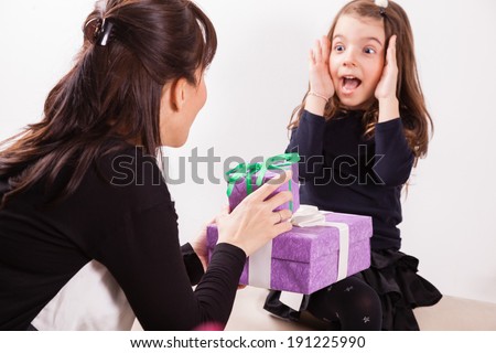 Mother giving her daughter a surprise gift.