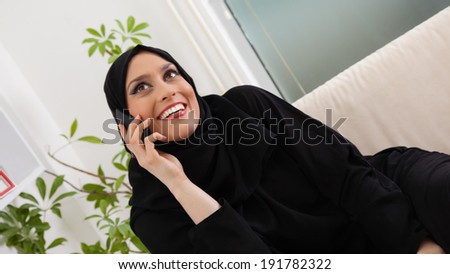 Middle Eastern Woman Having Phone Conversation On Sofa