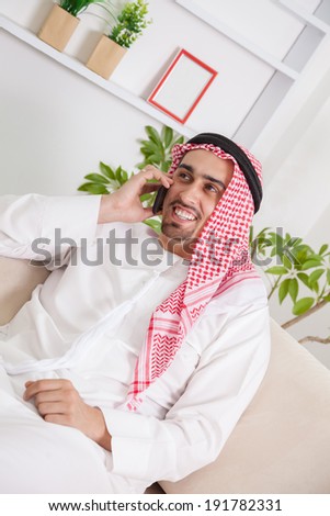 Middle Eastern Man Having Phone Conversation On Sofa