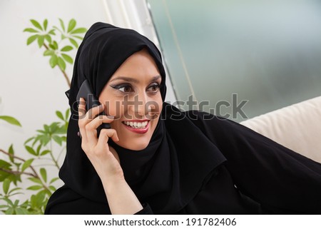 Middle Eastern Woman Having Phone Conversation On Sofa