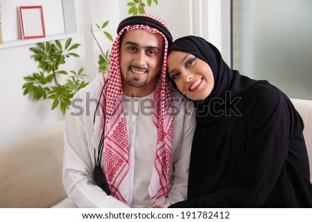 Portrait Of Young Arabic Couple Sitting On Sofa