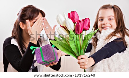 Cute little girl giving her mother flowers for Mother\'s day. Focus is on the flowers.