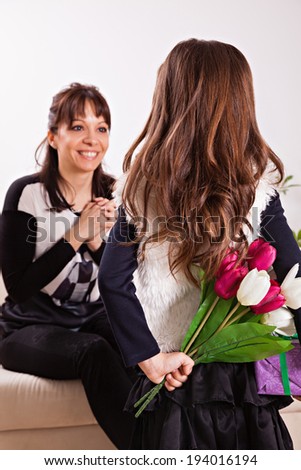 Cute little girl giving her mother flowers for Mother\'s day. Focus is on the girl.