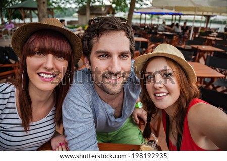 Three Young People In Cafe Taking Selfie.