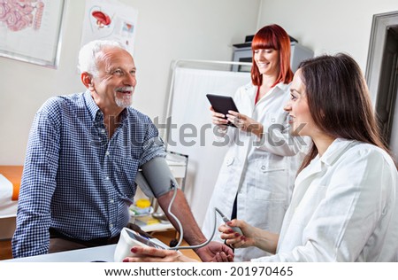 Doctor Checking Blood Pressure To A Mature Man At Doctor\'s Office.