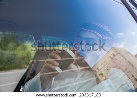 Arabian Businessman In Car Speaking On Smart Phone And Drinking Coffee