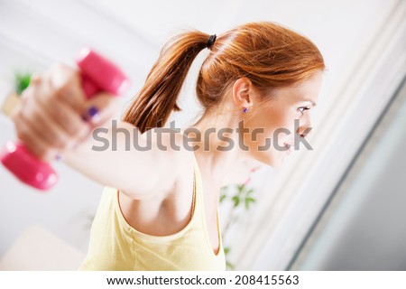 Beautiful Young Woman Exercising At Home With Dumbbells