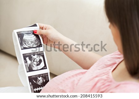 Pregnant Woman Looking At Ultrasound Scan Of Baby. Focus Is On Scan