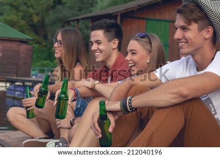 Group Of Cheerful Friends Chilling Near Lake
