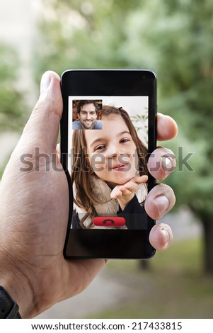 Close Up Of A Male Hand Holding A Smart Phone During A Video Call With His Daughter