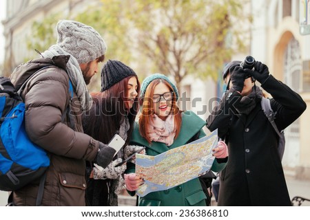 Group Of Young Tourists In The City Browsing Map Using Digital Tablet