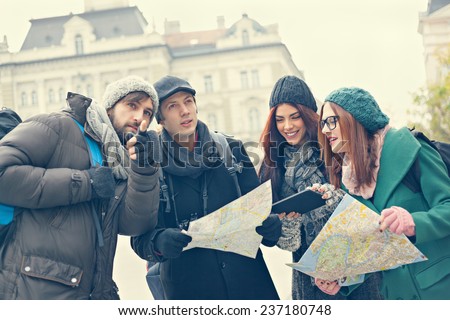Group Of Young Tourists In The City Browsing Map Using Digital Tablet