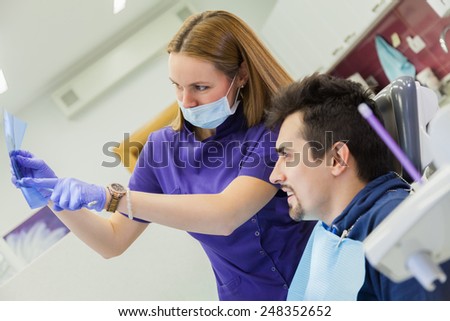 Dentist Together With Patient Looking At Patient X-ray Photography During Dental Examination