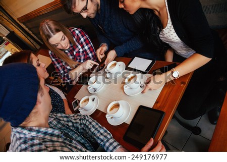 Group Of Young Friends Socializing In Cafe.